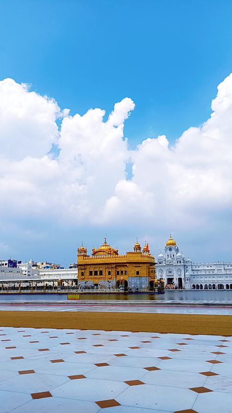 This may contain: a large building sitting next to a body of water under a blue sky with clouds