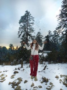 This may contain: a woman standing in the snow with her arms outstretched