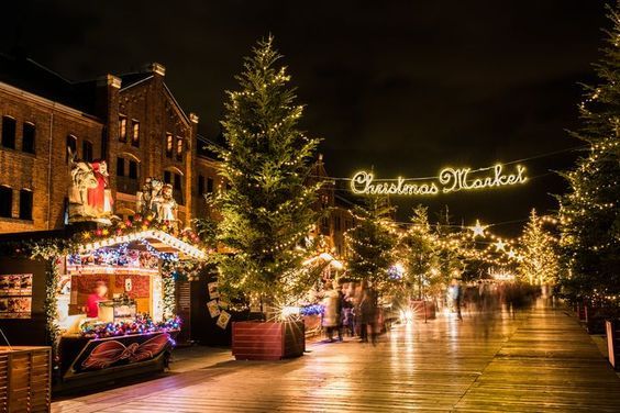 This may contain: people walking down a street decorated with christmas lights