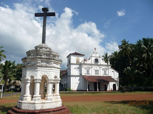 This may contain: a large white building with a cross on top and palm trees in the back ground