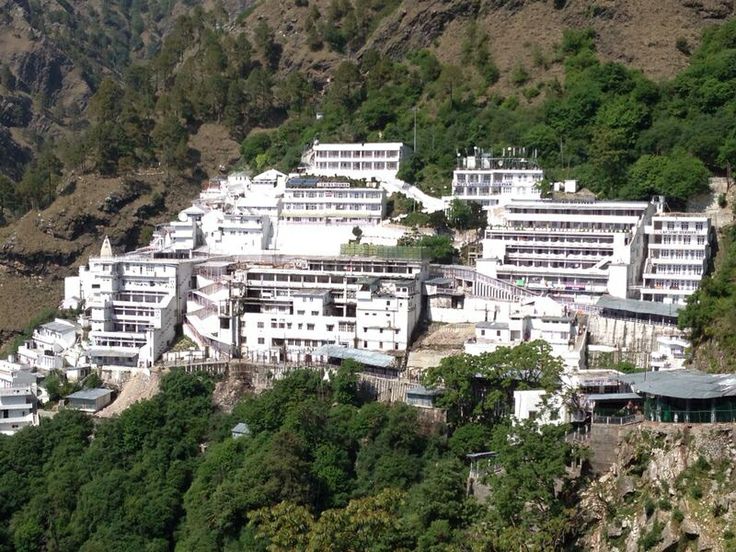 This may contain: a large white building on the side of a mountain with lots of trees around it