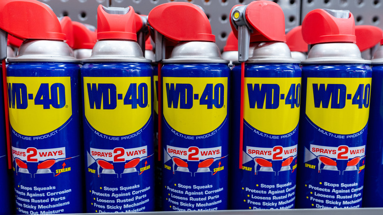WD-40 spray cans with red applicator nozzles lined on store shelf.