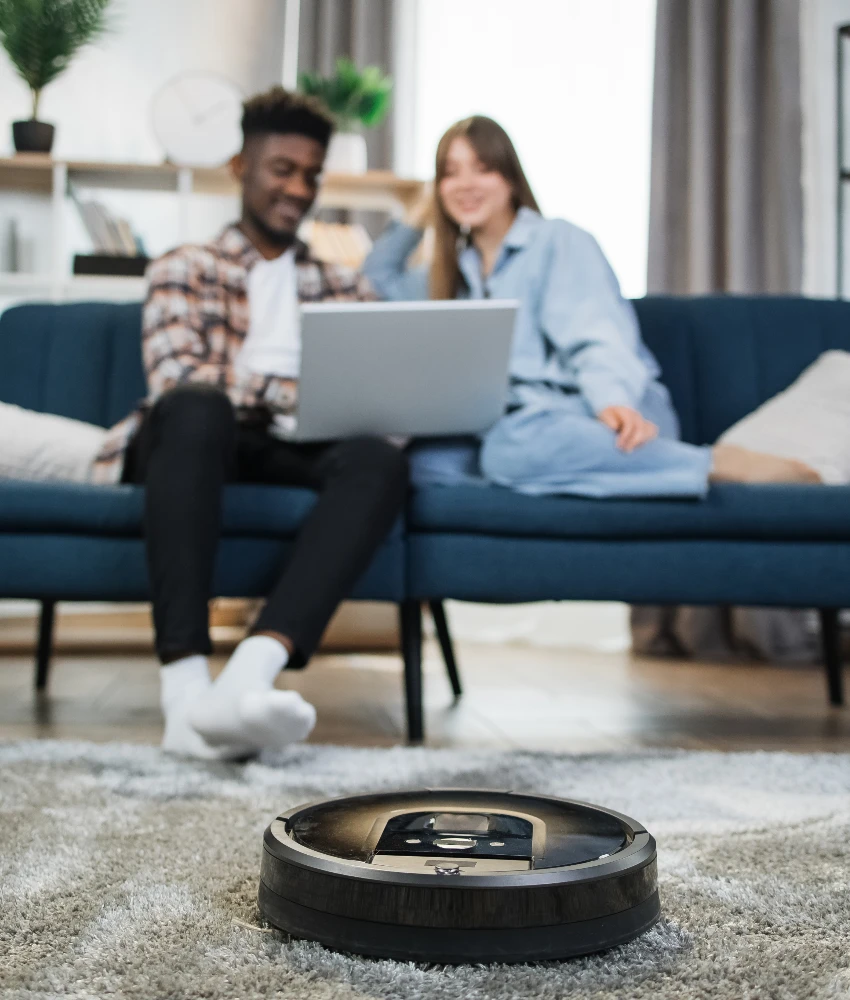 couple spending time together while roomba vacuum cleans floor