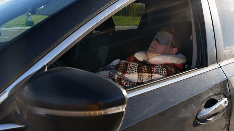 Drive with neck pillow and eye mask sleeps in car