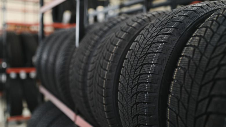 Several tires lined up side by side on an indoor storage rack.