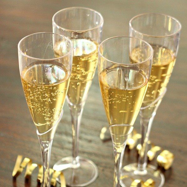 This may contain: four glasses filled with champagne sitting on top of a wooden table next to confetti