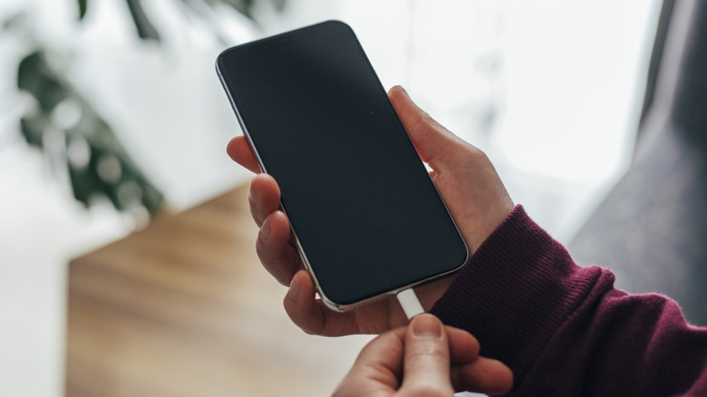 Person connecting USB-C cable to smartphone charging port