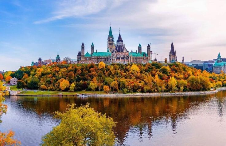 This may contain: a large castle sitting on top of a lush green hillside next to a body of water