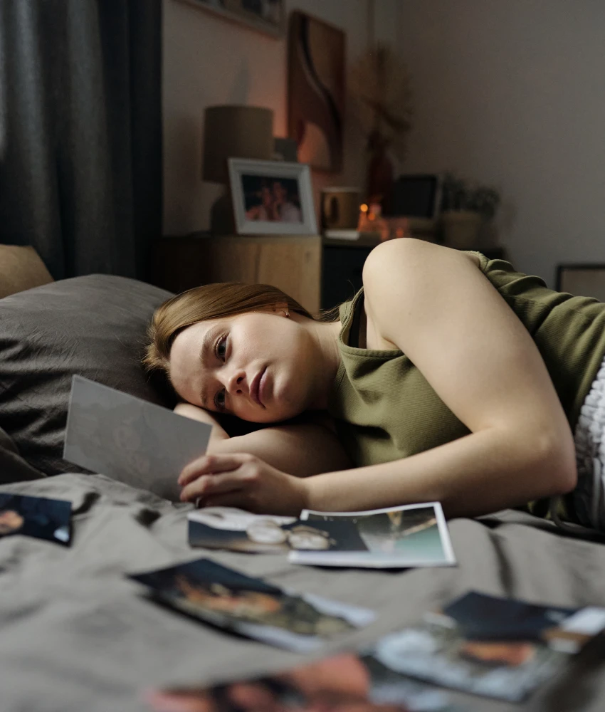 woman lying on bed looking at photos from her past