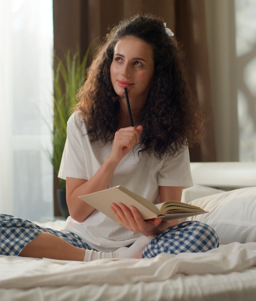 woman writing in book and thinking