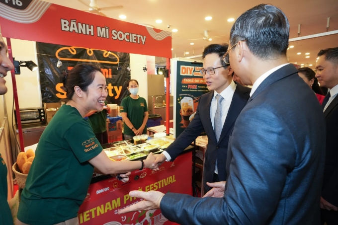 Mr. Tran Phuoc Anh, Vietnamese Ambassador to Singapore and Mr. Desmond Choo, Secretary of State, Ministry of National Defense of Singapore experienced Vietnamese bread and coffee at the Banh Mi Society booth in October 2025. Photo: NVCC.
