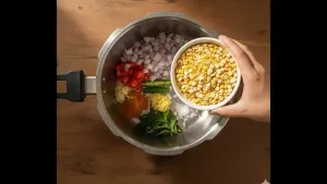 Soaked lentils drained and added to the pressure cooker along with finely chopped onion, tomato, chopped green chili, crushed garlic, grated ginger, curry leaves, turmeric powder, and salt.