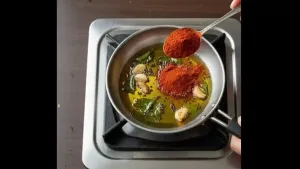 Heat lowered and red chili powder added quickly, stirred well to avoid burning the spices.