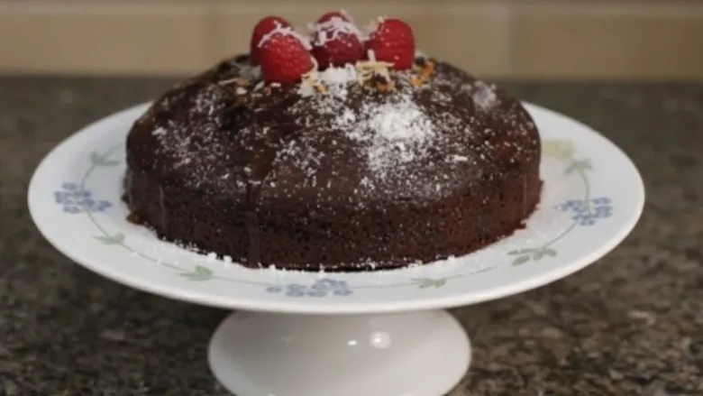 chocolate cake on cake stand with cherry toppings