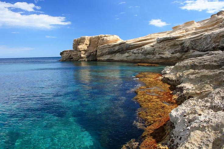 This may contain: the water is crystal blue and clear with some rocks on it's sides in front of an ocean cliff