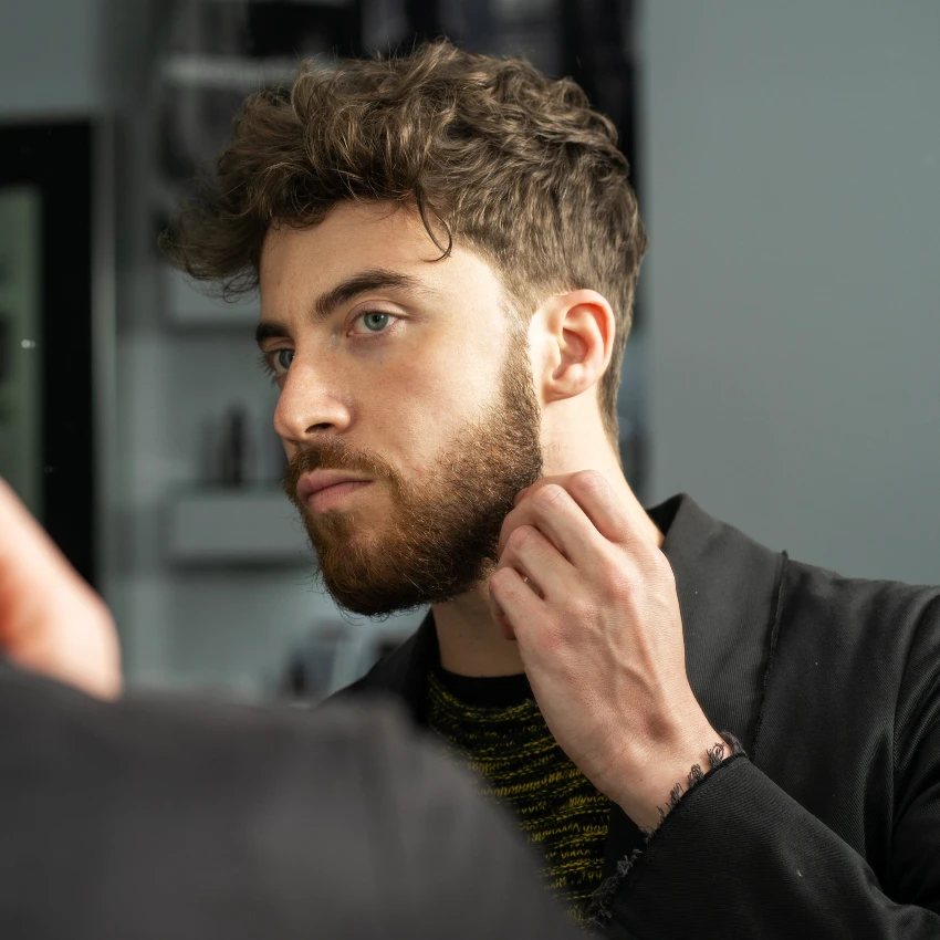 young man examining beard in mirror