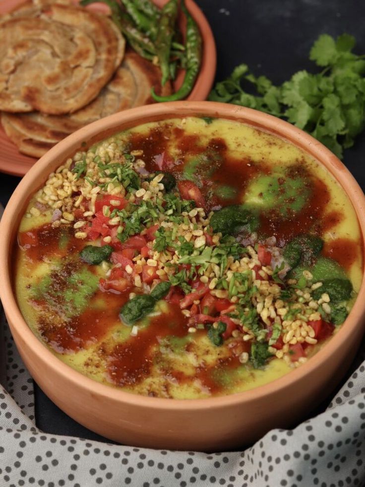 This may contain: two bowls filled with food sitting on top of a table next to crackers and bread