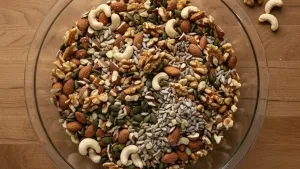 Bowl of mixed nuts and seeds on wooden table.