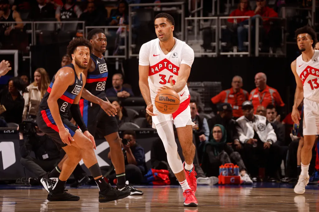 A Toronto Raptors player dribbles the ball down the court against the Detroit Pistons.