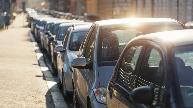 Numerous cars parked along a city sidewalk.