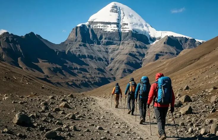 This may contain: group of hikers walking up a trail in front of a snow covered mountain range