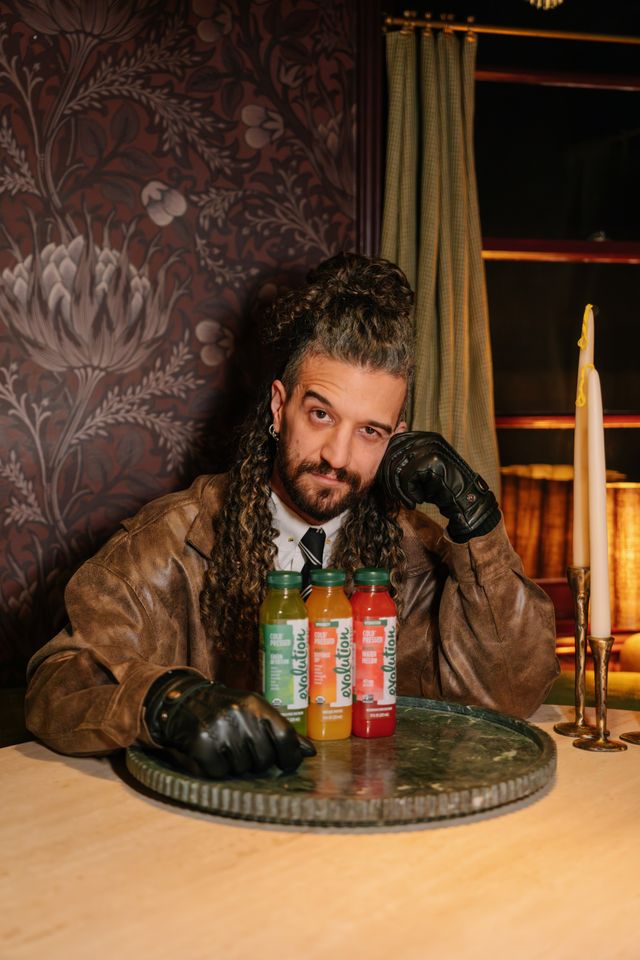 Mark Ballas seated indoors with bottled drinks placed on a tray in front of him Credit: Mark Ballas