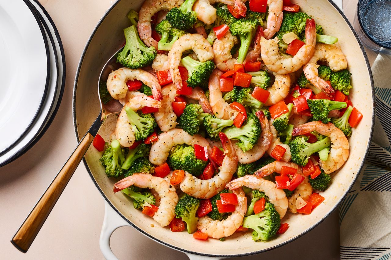 Skillet with cooked shrimp, broccoli, and diced red bell peppers Credit: Photographer: Greg Dupree; Food Stylist: Jennifer Wendorf;Prop Stylist: Josh Hoggle
