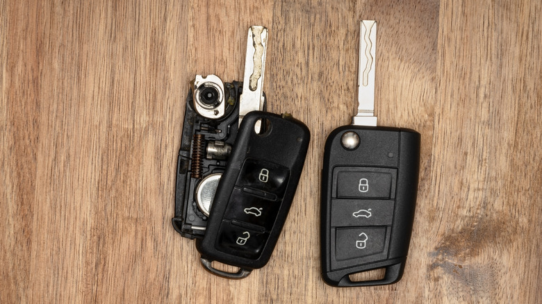 Two key fobs on a wood surface, one open with the battery exposed