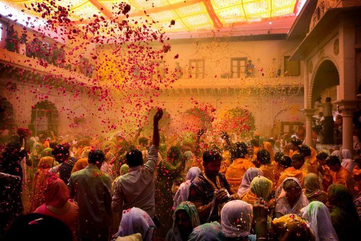 This may contain: many people are throwing colored powder on each other in the middle of a large room