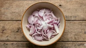 Thinly slice 2–3 large onions, place them in a bowl, add a little salt, and let them rest for 5 minutes so they soften slightly and release their flavor.