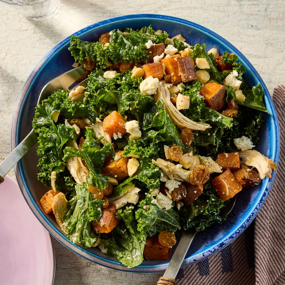 A bowl of kale and sweet potato salad with chicken and toppings served with utensils in it Credit: Photographer: Jen Causey, Food Stylist: Jennifer Wendorf, Prop Stylist: Phoebe Hausser.