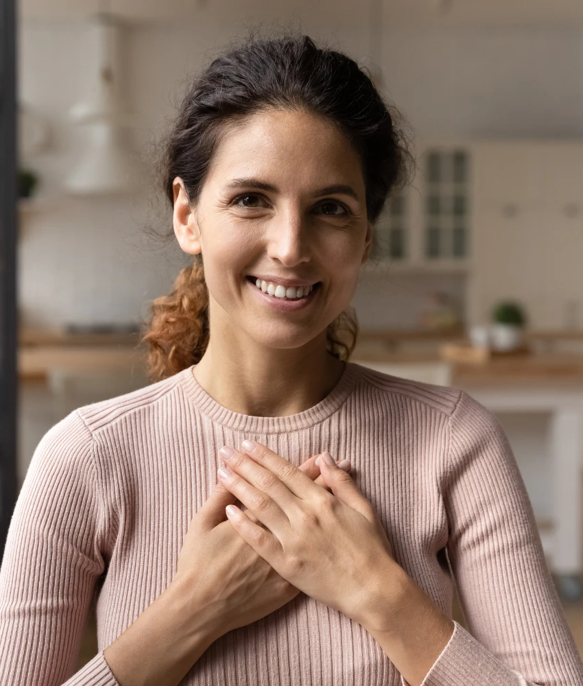 Woman in her 40s with hands over her heart