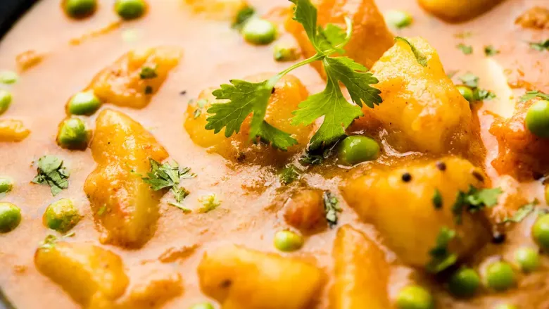 Spicy potatoes dish with some peas and coriander