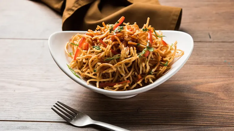 Plate of spicy Chinese bhel made with crispy noodles served in white bowl