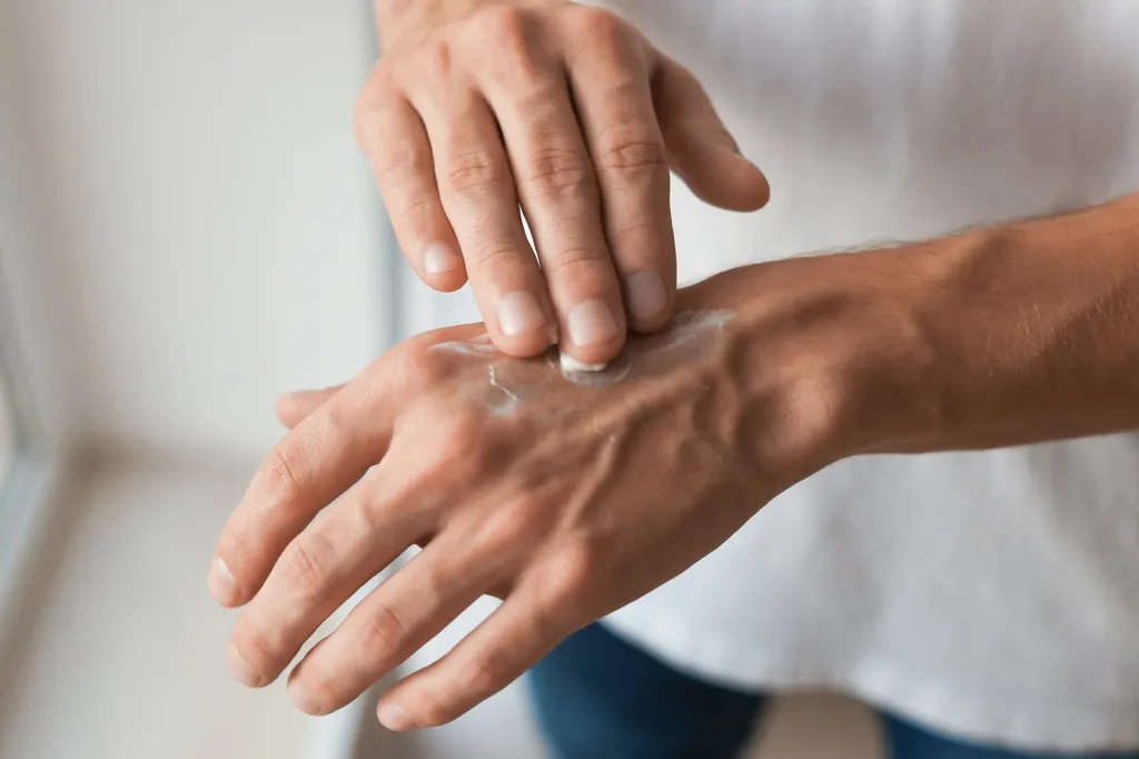 An image of a person placing lotion on their hands.