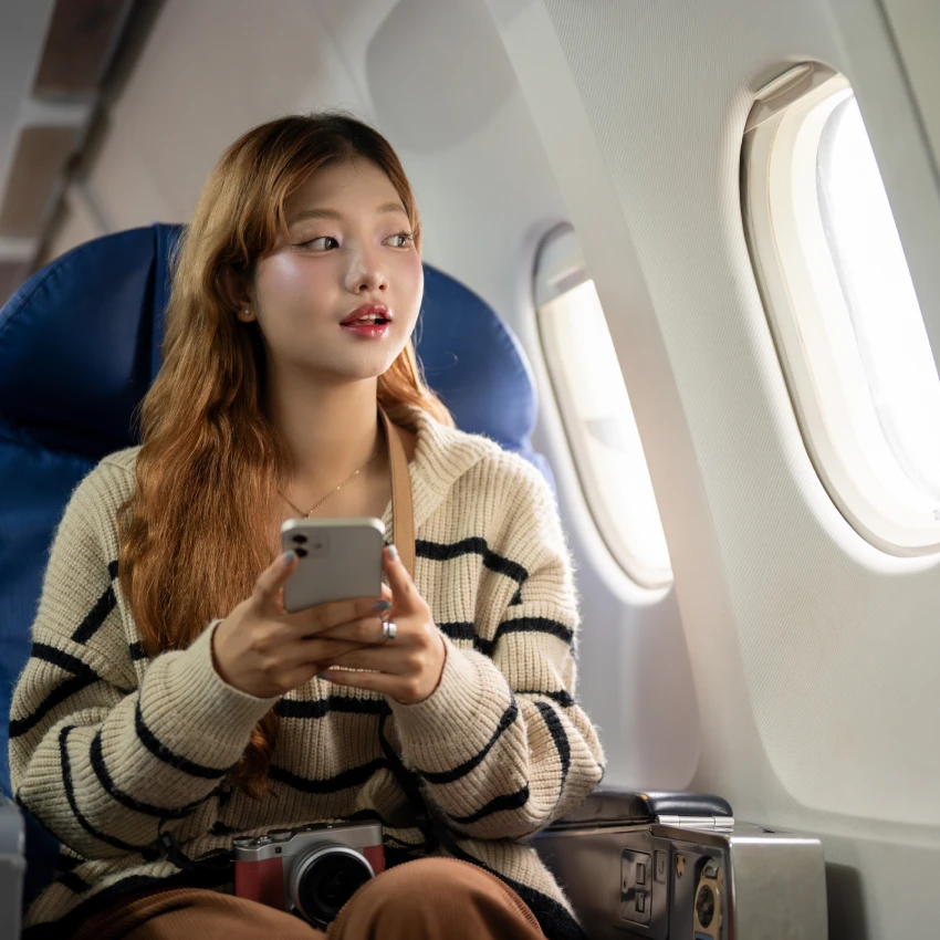 woman sitting on plane holding phone