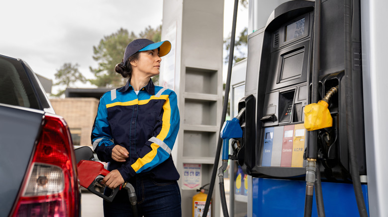 Female attendant refueling a car at a gas station