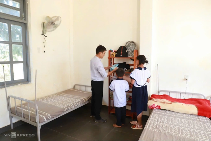 Teacher Hoang Van Ngoc (left), 39 years old, is instructing Ly Van Hoang (middle), 10 years old, and Ly Thi Ut, 11 years old, to fold clothes at the public affairs office, December 2025. Photo: Nga Thanh