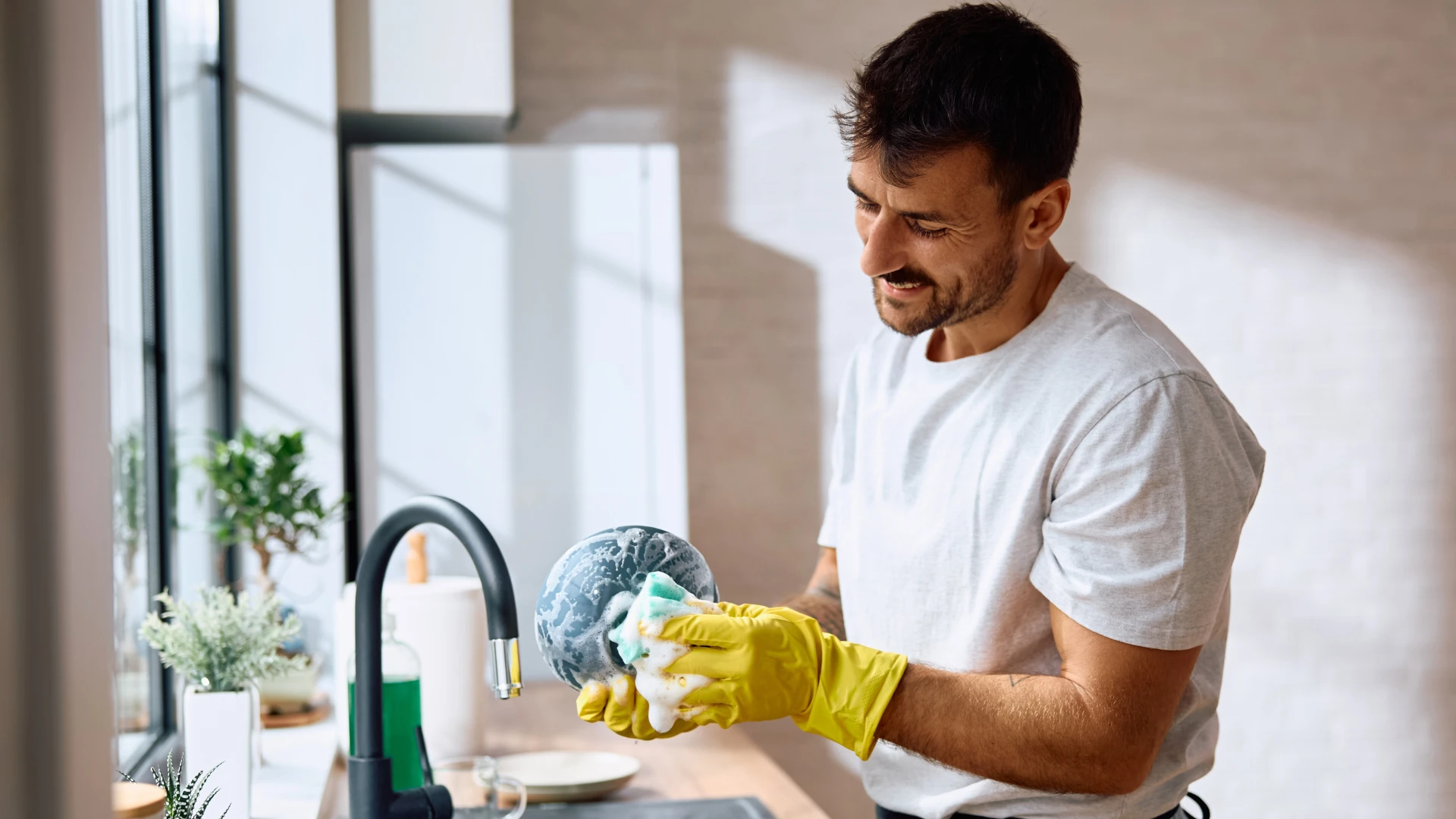 man using dirty sponges to clean dishes at home