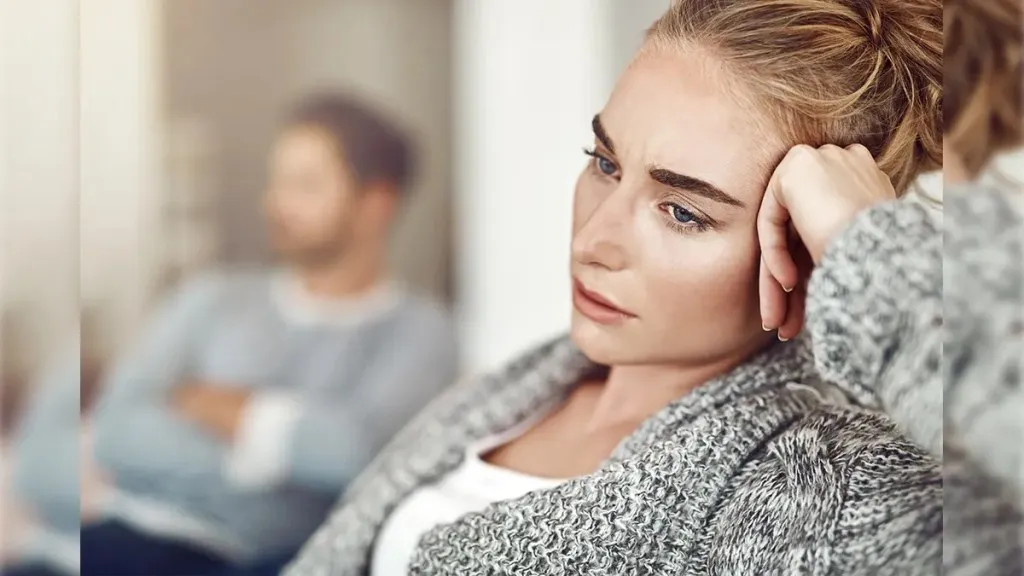 woman and man sitting together and woman keepin her hand on head