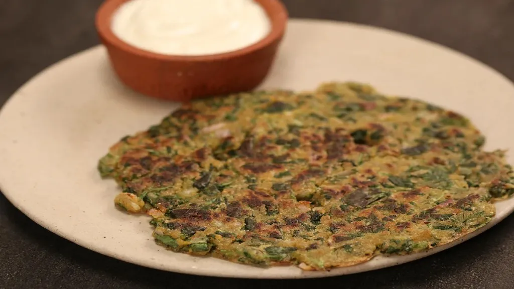 Jowar Methi Thalipeeth served in plate with curd