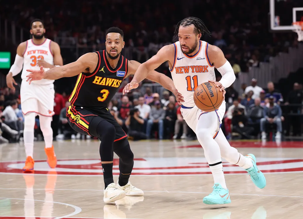 Jalen Brunson of the New York Knicks drives against CJ McCollum of the Atlanta Hawks during a basketball game.