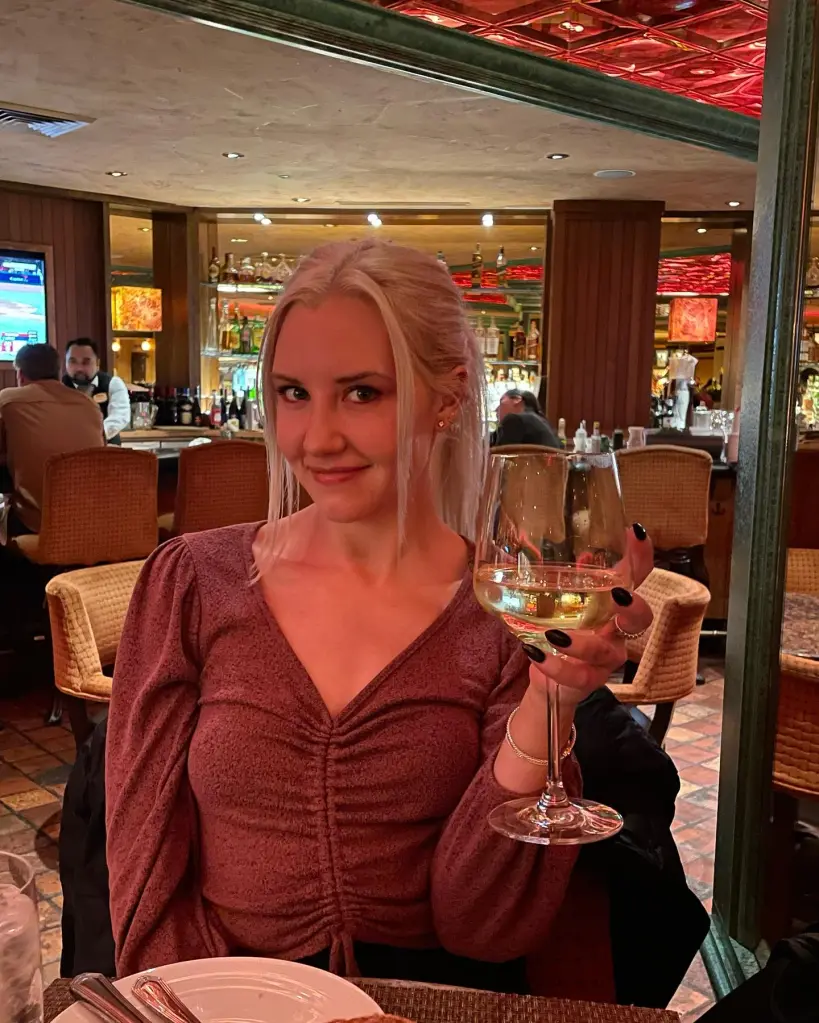 Lauren Harkins holding a glass of white wine at a bar.