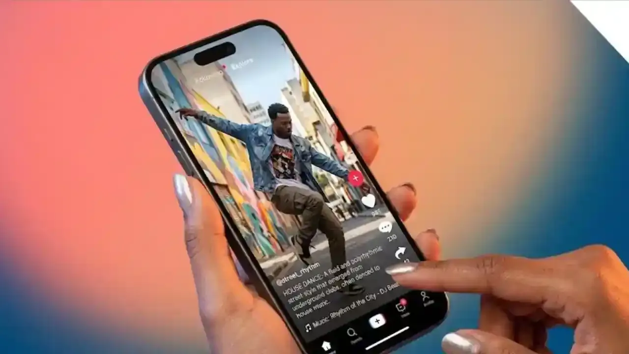 A person has a smartphone in his hand, in which Instagram/TikTok reel is playing. On the screen a creator is performing house dance on the street