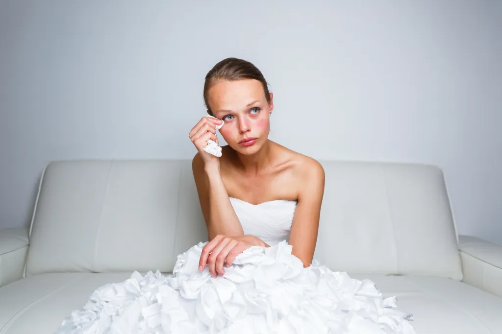Sad bride crying while sitting on a white couch.