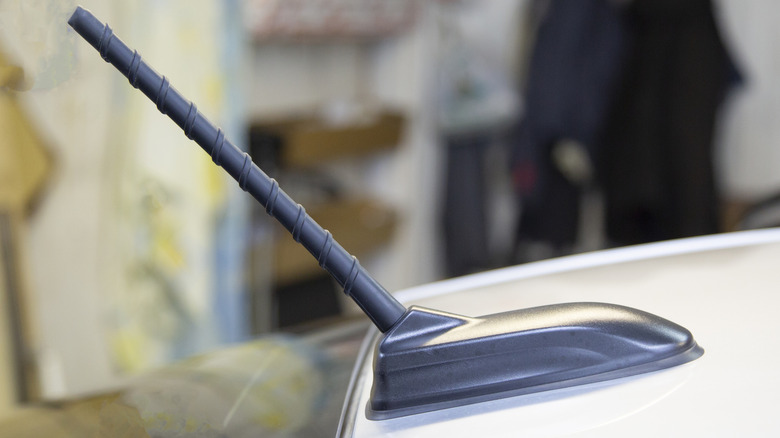 Side view of a spiral antenna on the roof of a silver car inside of a garage