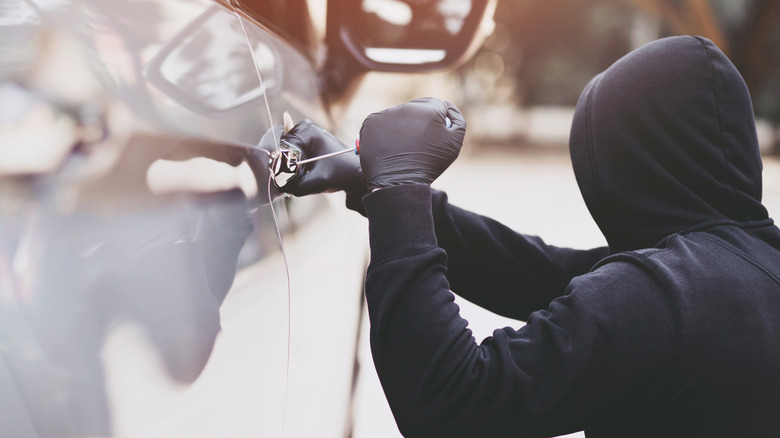 A person breaking into a vehicle.
