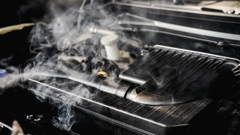 Close up of an overheating engine with smoke rising from it