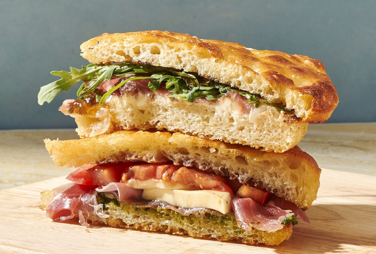 Stacked focaccia sandwiches filled with cured meat cheese tomato slices and arugula Credit: Diana Chistruga