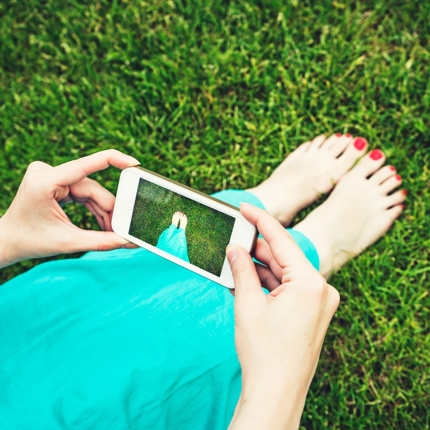 woman using smartphone to take pictures of feet outside